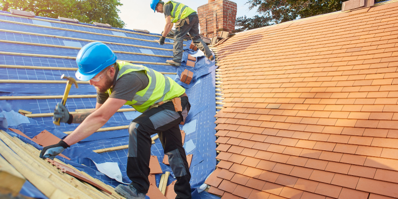 Two construction workers installing tiles during a professional roof replacement in Tampa.